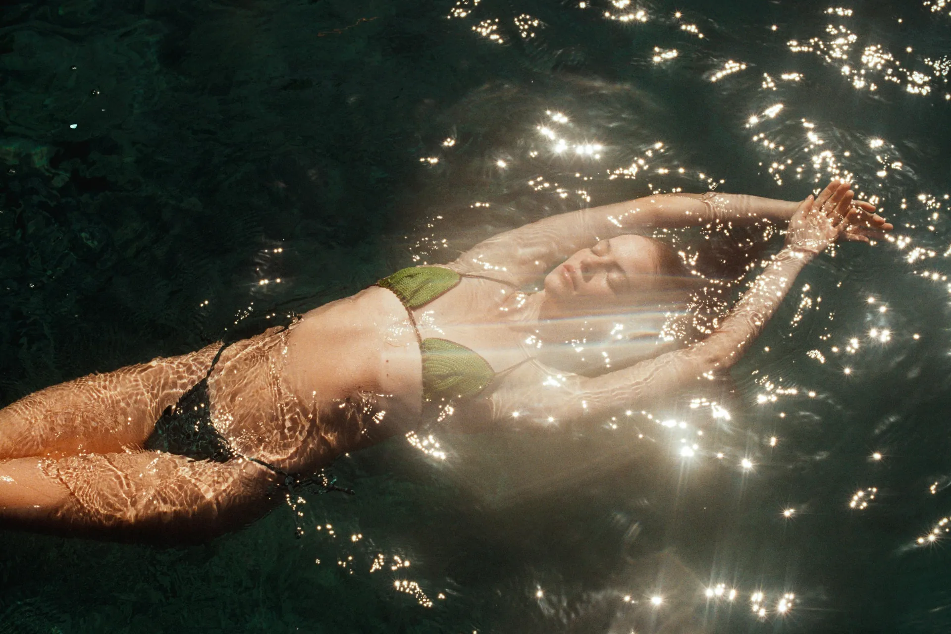 A model floating in the sea wearing SeaMiLeS shell jewelry